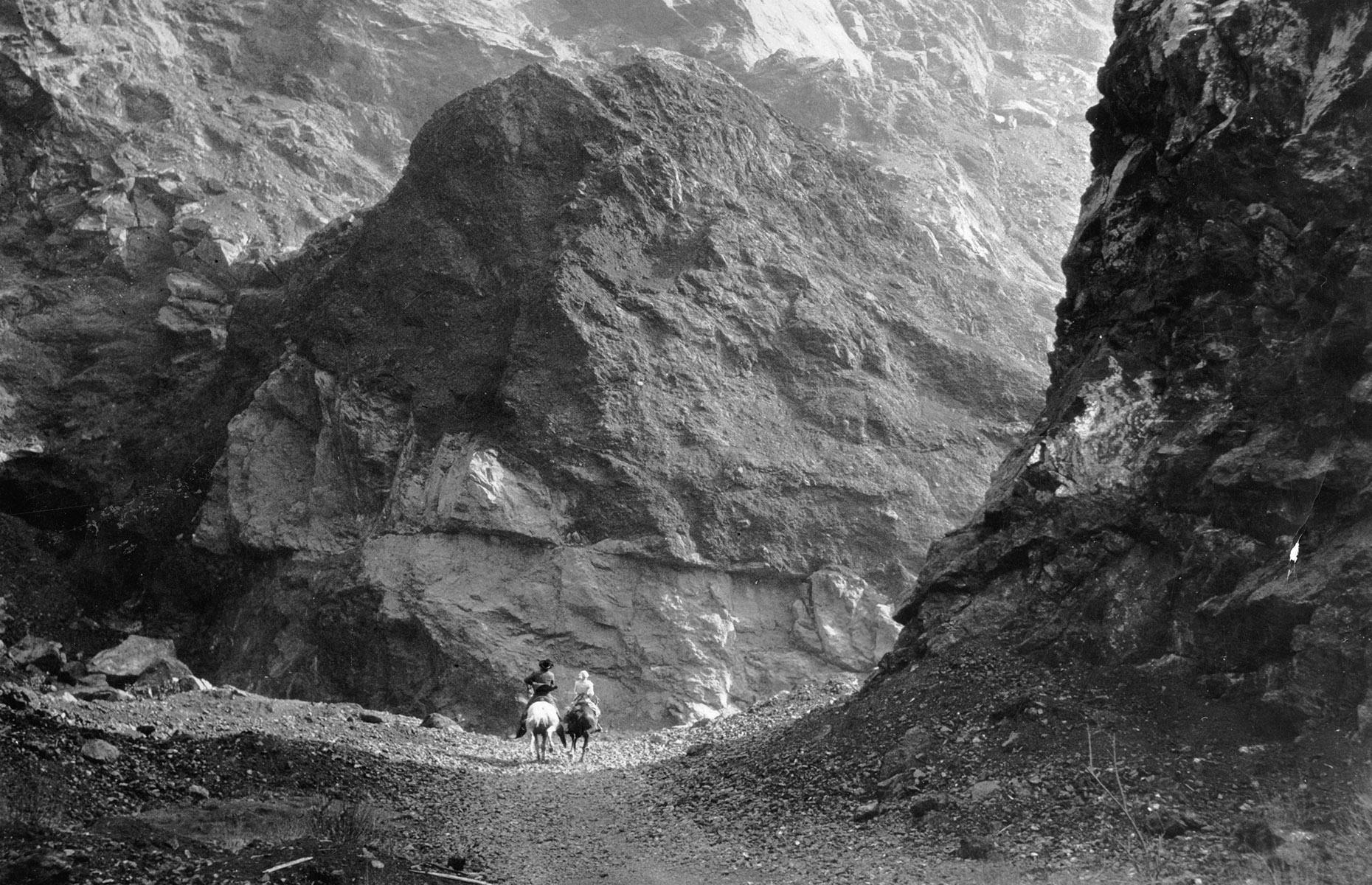 Road improvements continued in Yellowstone through the 1930s – but not everyone favored four wheels. This romantic image shows a pair of horse riders deep within the Grand Canyon of the Yellowstone River, circa 1935.