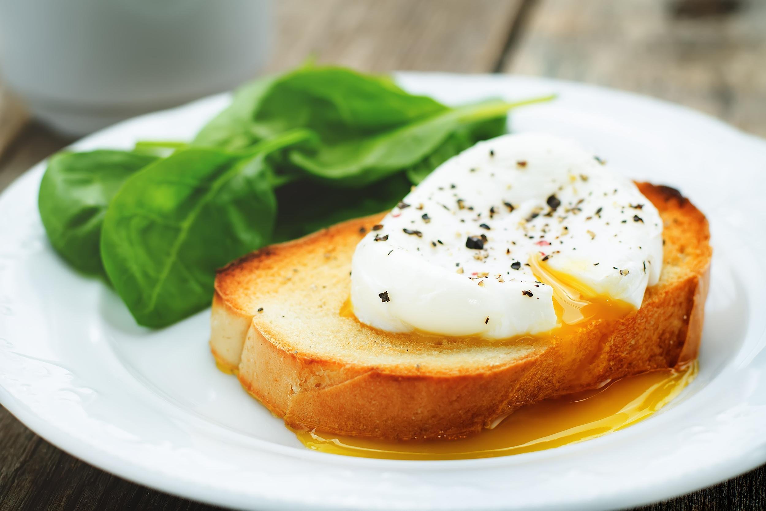 <p>The simplest use for poached eggs is to serve them on toast, although they're also an ingredient in <a href="https://blog.cheapism.com/breakfast-food-calories-17562/">recipes such as eggs Benedict</a>. Start by filling a saucepan with water 2 inches deep. Add one-half teaspoon vinegar and bring to a simmer — not a full boil. Meanwhile, break an egg (be sure it's fresh) into a small cup or bowl. When the water is simmering, stir it gently to create a slow whirlpool in the center of the pan. Slide the egg into the water (don't let it touch the bottom). The egg should cook for about 2 minutes for a runny yolk, and 4 minutes for a firm yolk. Remove the poached egg with a slotted spoon and place on paper towel to absorb excess water. For perfect results, serve poached eggs immediately, over toast.</p>