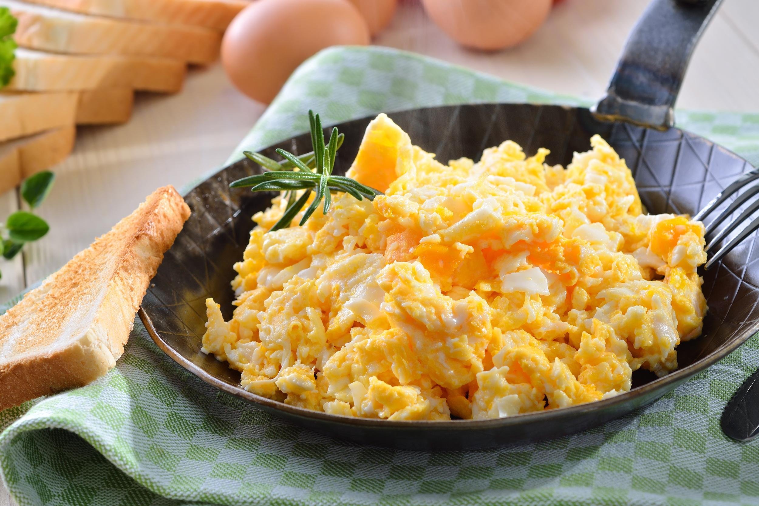<p>According to expert tips, a quick and easy way to make scrambled eggs, a breakfast staple, is to cook them slowly over medium-low heat, which gives them a fluffy texture. To scramble two eggs, crack them into a bowl with 2 tablespoons of milk or cream and use a whisk to beat together. (The dairy makes the eggs creamier and less bland, but it is optional.) Pour the contents of the bowl into a hot, buttered pan. Let the eggs sit for half a minute to a minute, until the bottom starts to set. Add pepper and salt to taste, along with any additional flavoring such as herbs or shredded sharp cheese. Use a silicone spatula or wooden spoon to move the eggs gently around the pan. After a minute or two, the eggs should start forming "curds" in the pan. When the eggs still look wet but there's no more liquid in the pan, turn off the heat. Like other fried eggs, scrambled eggs can be served with bacon or even in sandwiches for a perfect meal.</p>