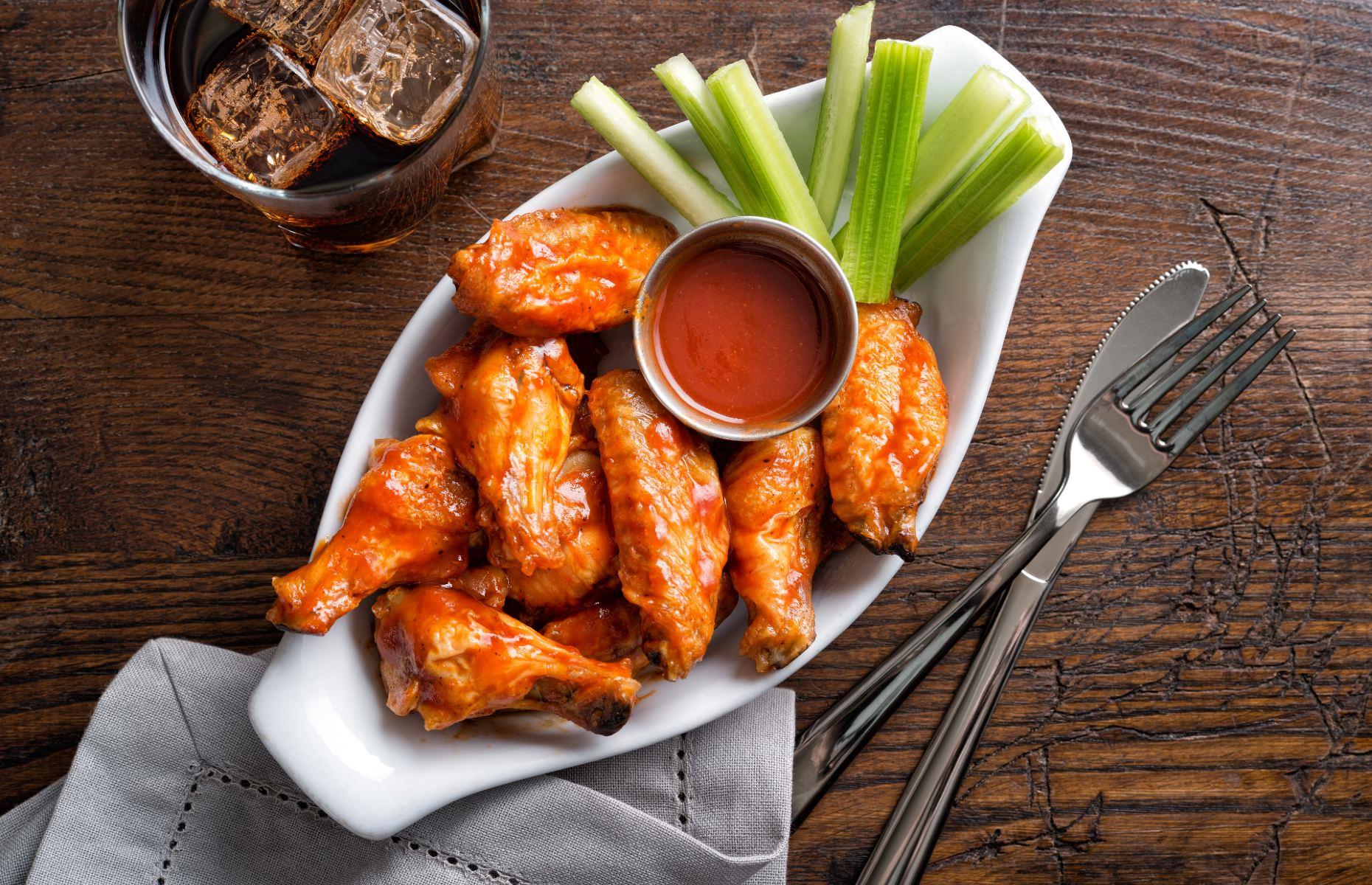 <p>As one of the most beloved dishes of the American cuisine, no US bucket list can be complete without eating Buffalo wings in its birthplace, Buffalo, New York. This sports bar classic gets its name from the Buffalo sauce in which the chicken wings are tossed in. One of the best ways to indulge in this fiery American dish is to take on the<a href="https://www.visitbuffaloniagara.com/crawl/buffalo-wing-trail/"> Buffalo Wing Trail</a>, which will guide you through 14 of the best Buffalo wings throughout the city.</p>