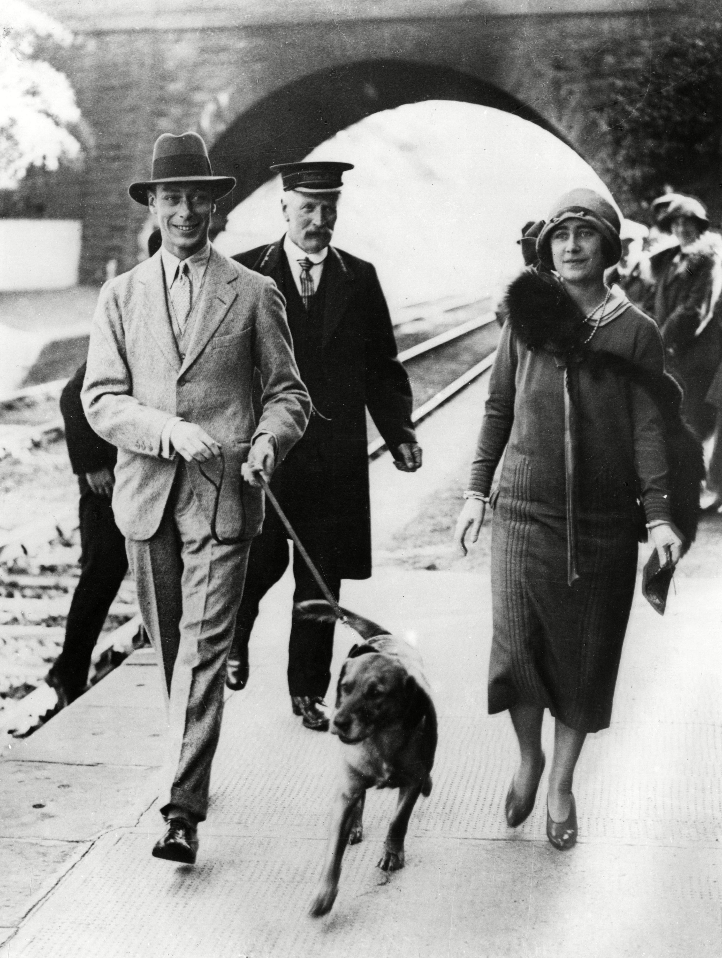 <p>A smiling King George VI and Queen Elizabeth, later the Queen Mother, are seen in an undated photograph at Ballater Railway Station in Scotland dressed informally and accompanied by a leashed dog and a railway worker. Ballater was at the time the closest railway station to their Scottish residence, Balmoral Castle.</p>