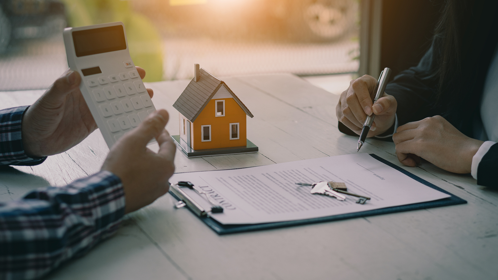 Real estate professionals offer their clients contracts to discuss home purchases, insurance or real estate loans. Home sales agents sit at the office with new home buyers in the office.