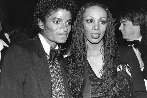 Slide 10 of 42: In this photo from 1982, the changes in his face are already noticeable. He is standing next to pop queen Donna Summer.