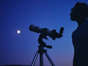 Telescopes at Walmart: Image shows man standing next to telescope looking at moon