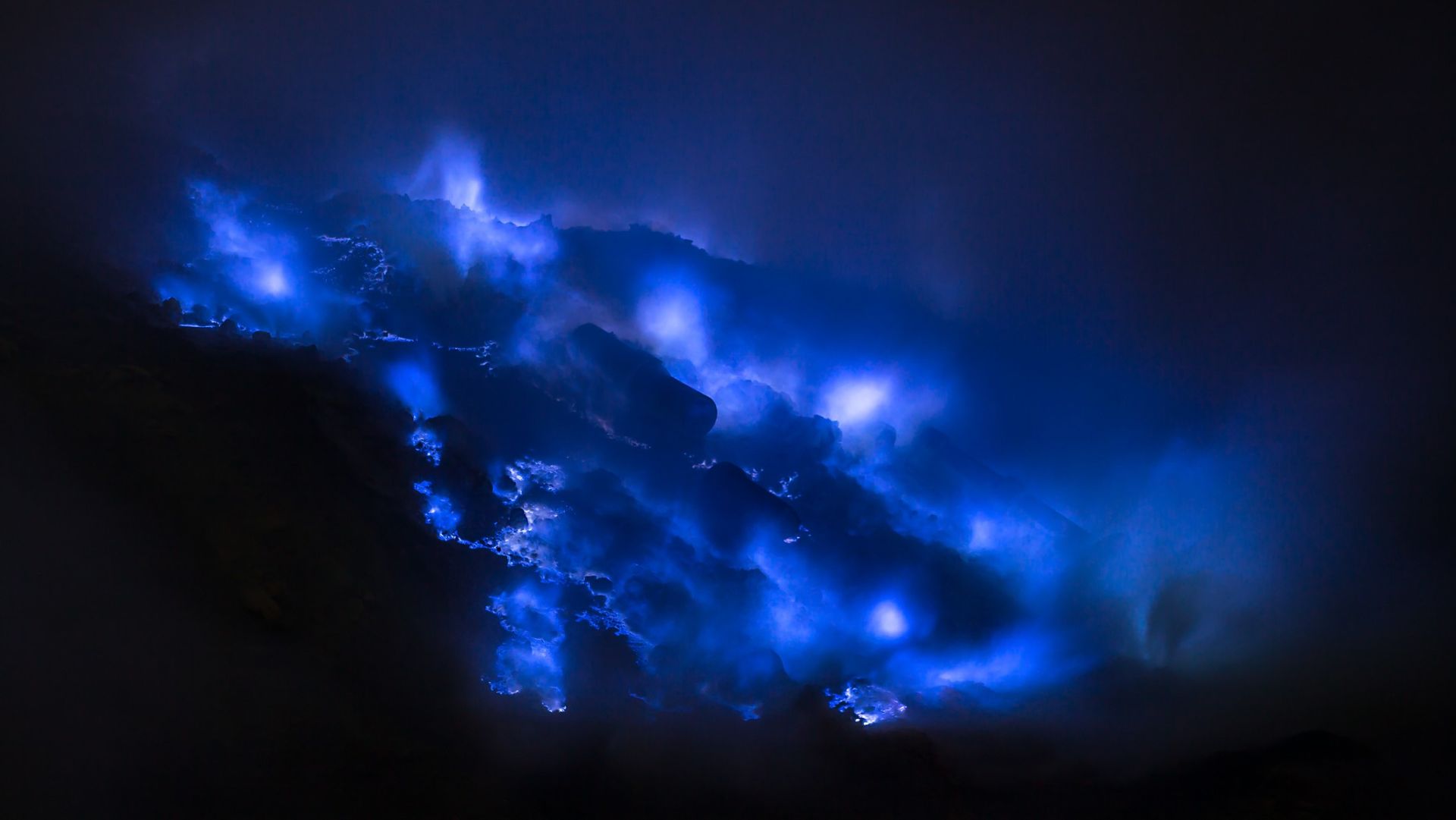 <p>                     The electric-blue rivers ejected from Kawah Ijen volcano in eastern Java look like something from another world.                   </p>                                      <p>                     Contrary to what is commonly reported, the lava itself is not blue. The striking color is a result of volcanic sulfur emissions. According to Geology.com), the volcano emits sulfurous gases that ignite when they meet Earth's oxygen-rich atmosphere and burn with a rich blue flame. When the sulfurous gas condenses, it produces the infamous blue rivers that illuminate the volcanic landscape at night.                    </p>                                      <p>                     According to Smithsonian Magazine, the eerie blue glow is only visible at night because it's the flames that are blue rather than the lava itself. It looks like any other volcano during the daytime.                   </p>
