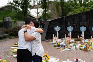 Lori Weisskopf (R) of Highland Park embraces her son Jeremy, at a makeshift memorial for victims of the 4th of July mass shooting in downtown Highland Park, Illinois on July 6, 2022.