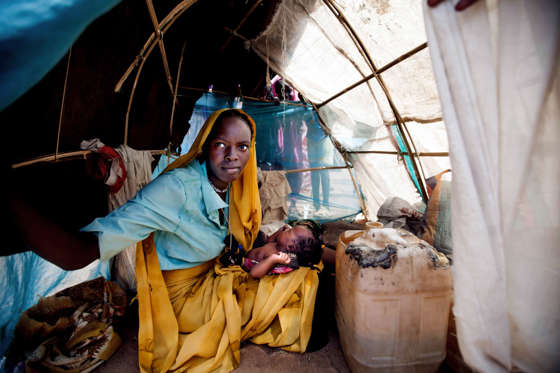 In this photo taken Sunday, March 9, 2014 and released by the United Nations African Union Mission in Darfur (UNAMID), Ashia Saleh, from Barkatil village holds her baby inside a make shift tent at the Kalma refugee camp for internally displaced people, south of the Darfur town of Nyala, Sudan. Thousands have been recently displaced following looting and destruction of a number of villages in South Darfur. At least 20, 000 have settled in refugee camps in Nyala. Women and children complain about the lack of food, water, and shelter. (AP Photo/UNAMID, Albert Gonzalez Farran)