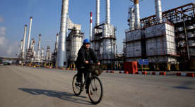 In this Monday, Dec. 22, 2014 photo, an Iranian oil worker rides his bicycle at the Tehran's oil refinery south of the capital Tehran, Iran.