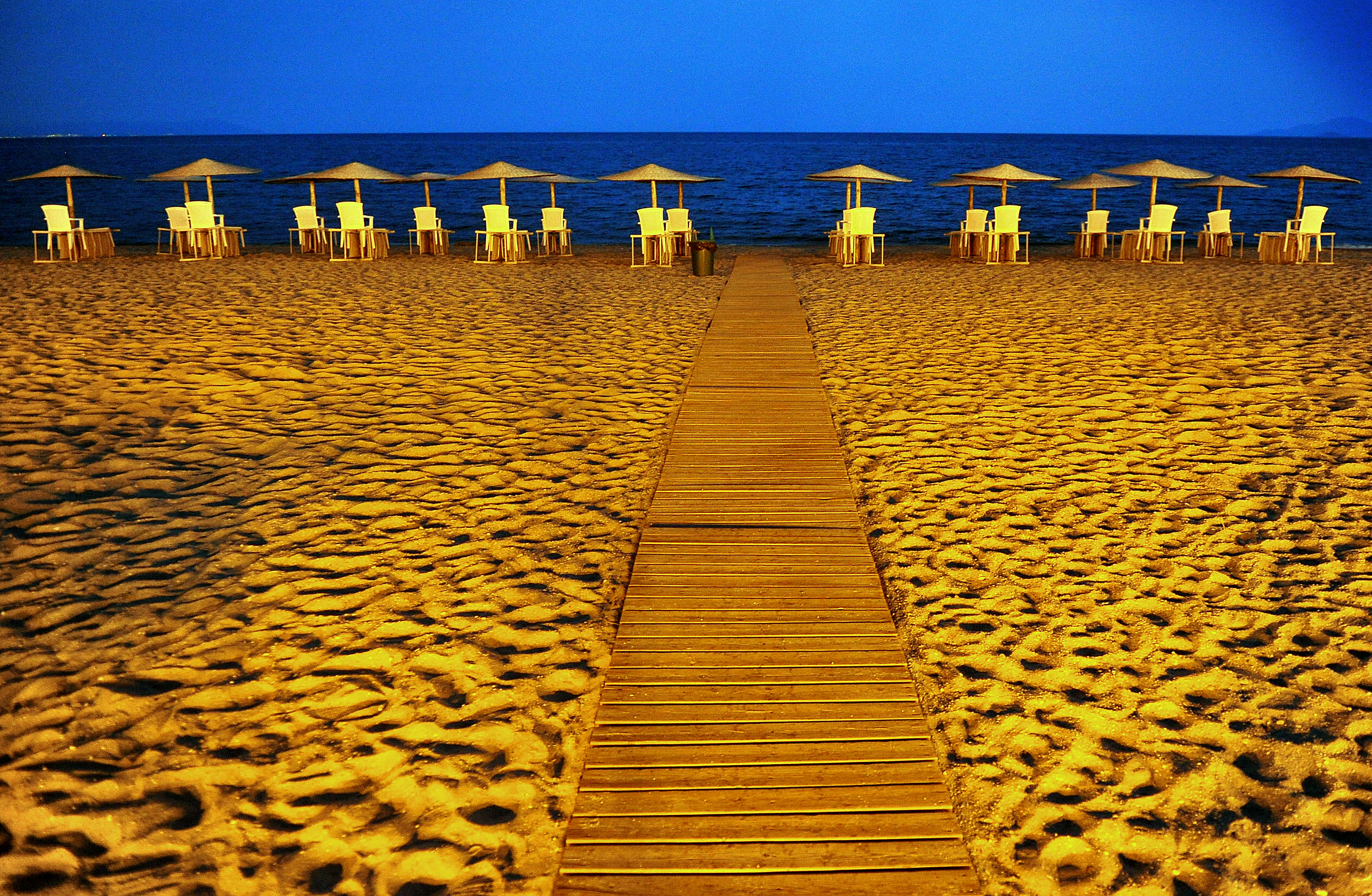 ÎÎ¹Î±ÏÎ¬Î½ÎµÎ¹Î± 42 Î±ÏÏ 42: Bloomberg's Best Photos 2013: Straw parasols stand above empty tables and chairs in evening light on a beach in Asprovalta, Greece, on Sunday, July 21, 2013. For Prime Minister Antonis Samaras, the tangible signs of Greece's recovery are the tourists pouring into Athens from cruise ships and airplanes.