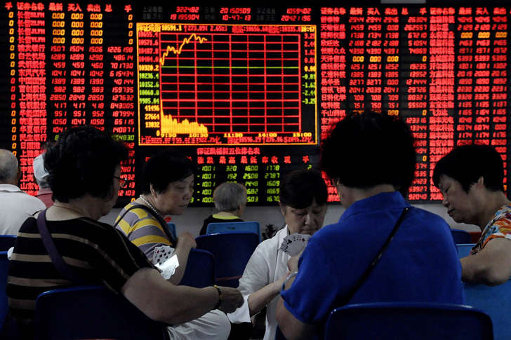 Investors play cards in front of an electronic board showing stock information at a brokerage house in Shanghai, China, September 9, 2015.