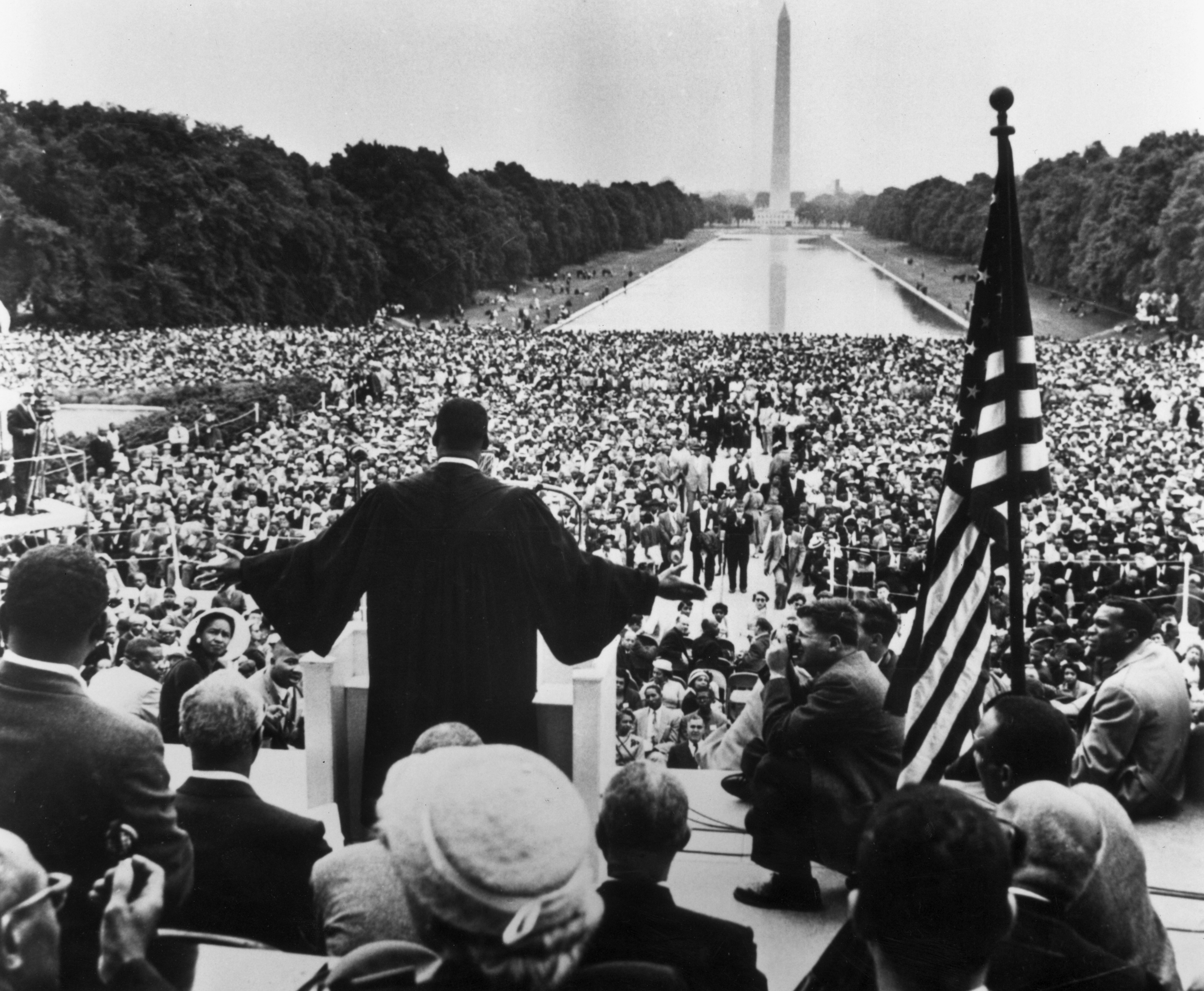 Slide 12 de 27: 17th May 1957: Back view of American civil rights leader and Baptist minister Martin Luther King, Jr. (1929 - 1968), dressed in black robes and holding out his hands towards the thousands of people who have gathered to hear him speak near the Reflecting Pool in Washington, DC during the Prayer Pilgrimage. The Washington Monument can be seen in the background. (Photo by Hulton Archive/Getty Images)
