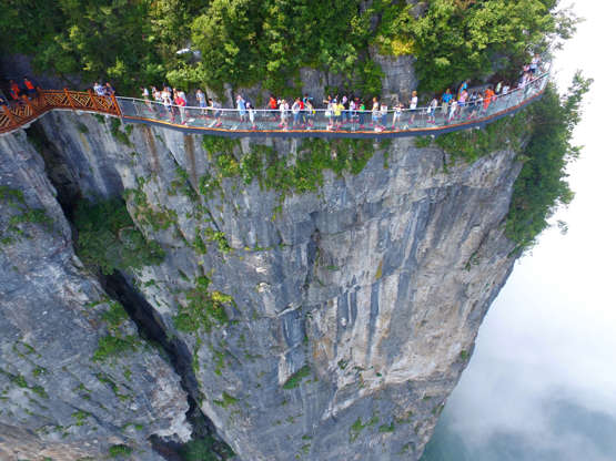 ÎÎ¹Î±ÏÎ¬Î½ÎµÎ¹Î± 23 Î±ÏÏ 24: ZHANGJIAJIE, CHINA - AUGUST 01:  Aerial view of tourists walking on the 100-meter-long and 1.6-meter-wide glass skywalk clung the cliff of Tianmen Mountain (or Tianmenshan Mountain) in Zhangjiajie National Forest Park on August 1, 2016 in Zhangjiajie, Hu