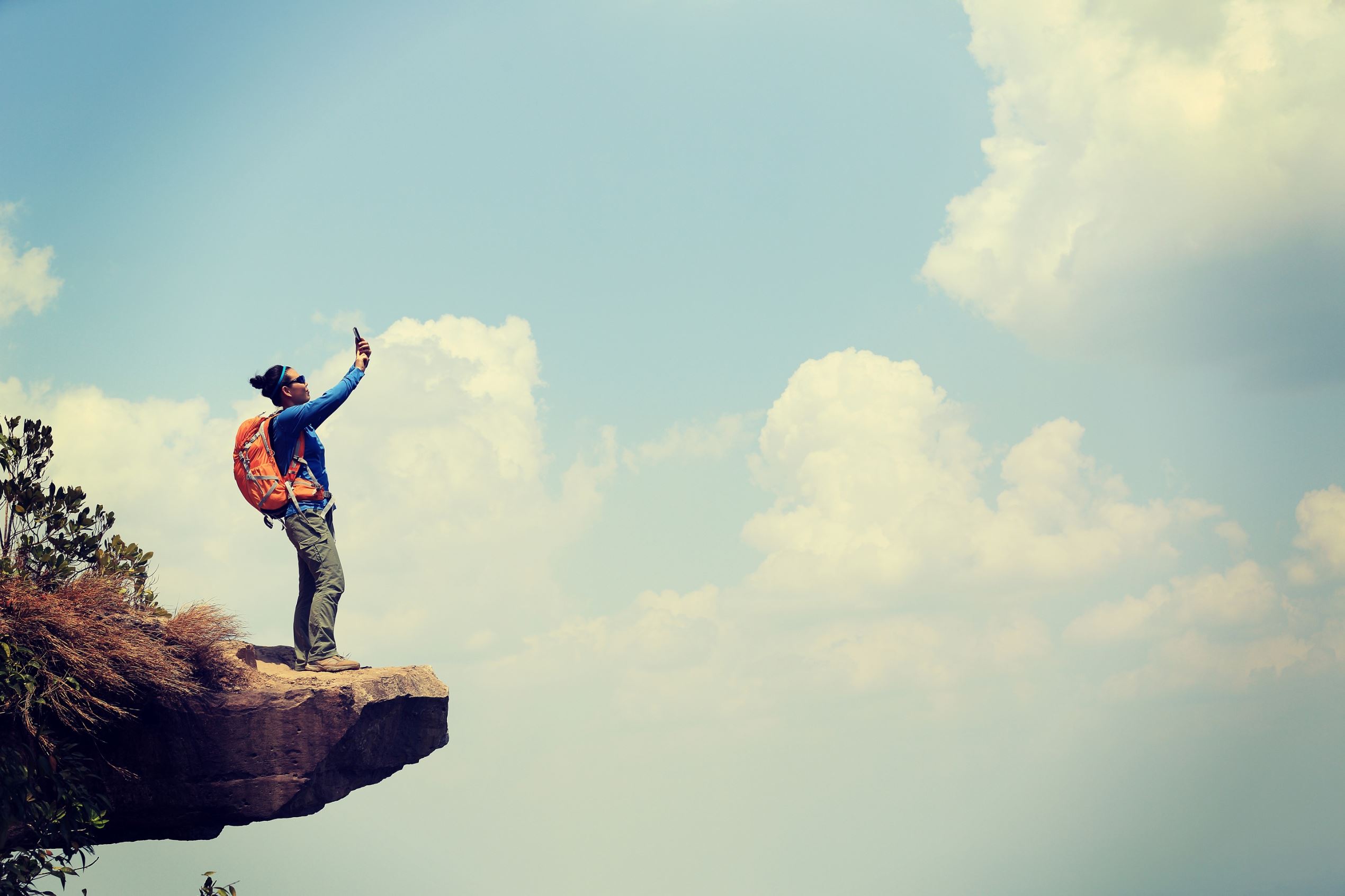 successful woman hiker taking photo on mountain top rock