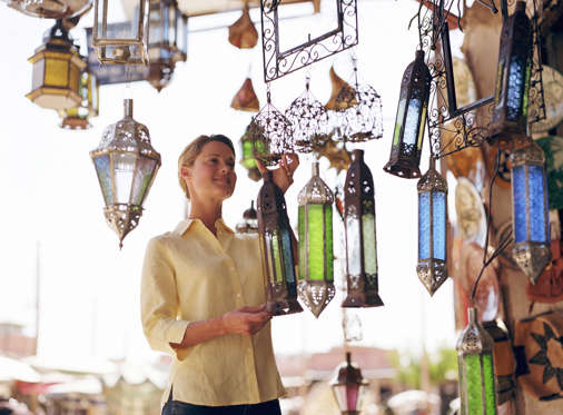 Young woman looking at lamp shades in shop.