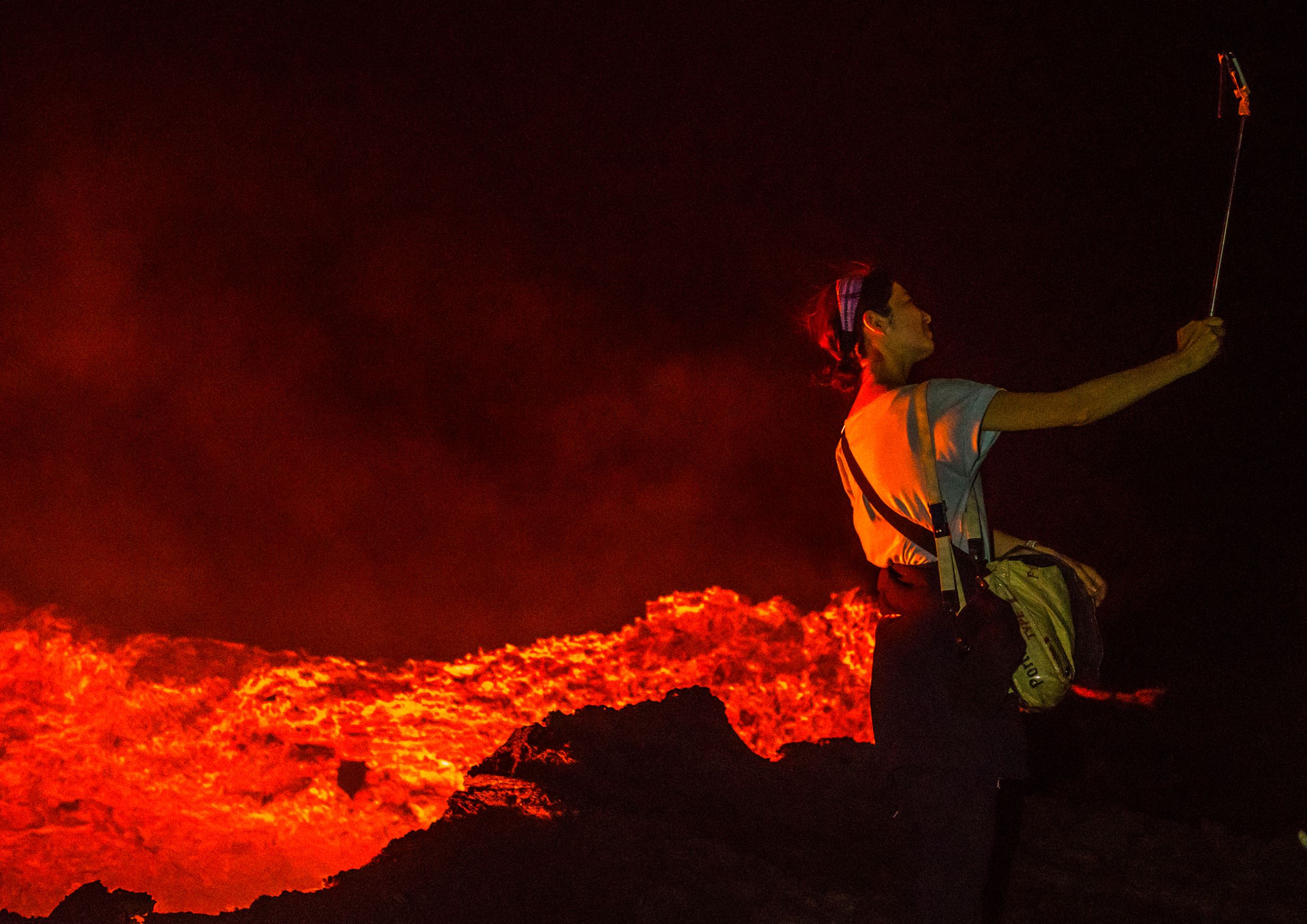ERTA ALE, ETHIOPIA - FEBRUARY 27: Tourist taking a selfie in front of the living lava lake in the crater of erta ale volcano, afar region, erta ale, Ethiopia on February 27, 2016 in Erta Ale, Ethiopia.  (Photo by Eric Lafforgue/Art in All of Us/Corbis via Getty Images)