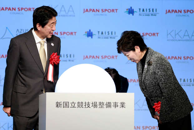 21 枚のスライドの 6 枚目: Japanese Prime Minister Shinzo Abe, left, is greeted by Tokyo Gov. Yuriko Koike after a groundbreaking ceremony of new national stadium in Tokyo, Sunday, Dec. 11, 2016.