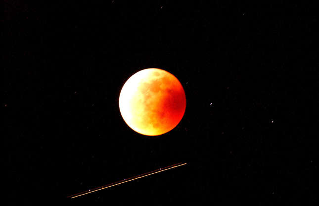 Slide 3 of 53: JOSHUA TREE NATIONAL PARK, CA - MAY 15: A jet flying toward Arizona from Los Angeles streaks past a totally eclipsed moon on May 15, 2003 over Joshua Tree National Park, California. It has been three years since North Americans last witnessed the moon completely darkened by the earth's shadow. (Photo by David McNew/Getty Images)