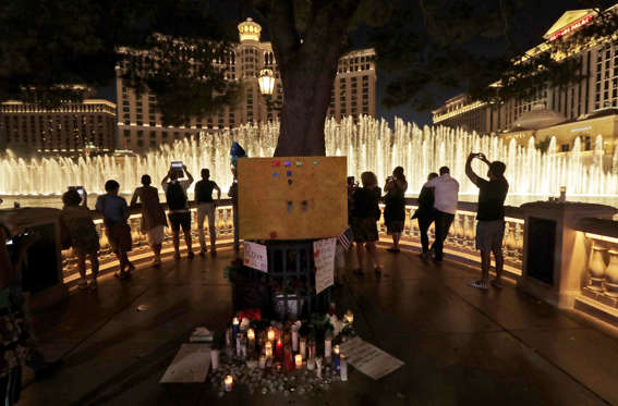 Slide 1 of 68: People take photos of the fountain at the Bellagio hotel in front of a memorial for victims of the mass shooting in Las Vegas, Tuesday, Oct. 3, 2017.