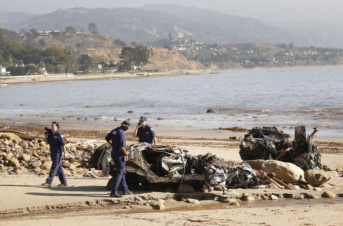 Slide 20 of 78: MONTECITO, CA - JANUARY 11:  Alisha Kleinman, Steve Knight, and Brett Weideman, left to right, members of the US Coast Guard  inspect two crushed vehicles, a Hummer and a Honda that were found on the beach January 11, 2018 after a rainstorm sent mud and debris through Montecito neighborhoods. (Photo by Al Seib/Los Angeles Times via Getty Images)