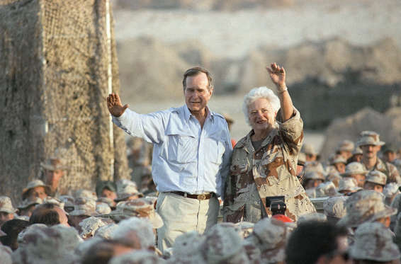Slide 13 of 28: Pres. George H. W. Bush, left, and First Lady Barbara Bush wave to U.S Marines at the desert encampment during a thanksgiving visit, Thursday, Nov. 22, 1990, Saudi Arabia.