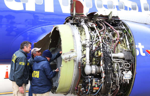 Slide 2 of 6: National Transportation Safety Board investigators examine damage to the engine of the Southwest Airlines plane that made an emergency landing at Philadelphia International Airport in Philadelphia on Tuesday, April 17, 2018. The Southwest Airlines jet blew the engine at 32,000 feet and got hit by shrapnel that smashed a window, setting off a desperate scramble by passengers to save a woman from getting sucked out. She later died, and seven others were injured.