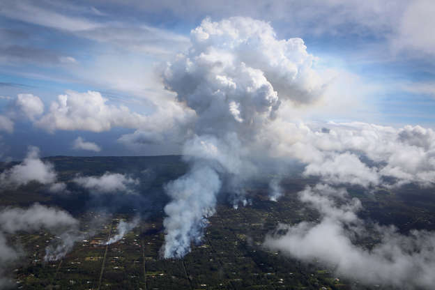 Slide 1 of 66: A plume of gas mixed with smoke from fires caused by lava rises (C) amidst clouds in the Leilani Estates neighborhood in the aftermath of eruptions from the Kilauea volcano on Hawaii's Big Island on May 6, 2018 in Pahoa, Hawaii. A magnitude 6.9 earthquake struck the island May 4. The volcano has spewed lava and high levels of sulfur gas into communities, leading officials to order 1,700 to evacuate. Officials have confirmed 26 homes have now been destroyed by lava in Leilani Estates.