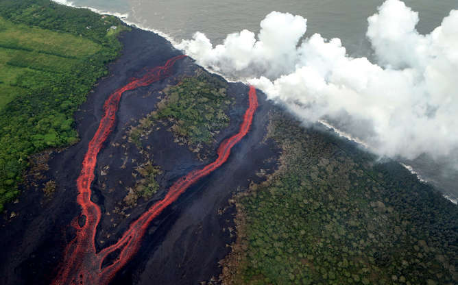 Slide 1 of 176: Steam plumes rise as lava enters the Pacific Ocean, after flowing to the water from a Kilauea volcano fissure, on Hawaii's Big Island on May 21, 2018 near Pahoa, Hawaii. Officials are concerned that 'laze', a dangerous product produced when hot lava hits cool ocean water, will affect residents. Laze, a word combination of lava and haze, contains hydrochloric acid steam along with volcanic glass particles.