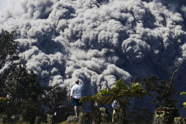 Slide 5 of 176: Jack Jones, visiting from Madison, Wis., takes pictures at a country club in Volcano, Hawaii as a huge ash plume rises from the summit of Kiluaea volcano Monday, May 21, 2018. Kilauea has burned some 40 structures, including two dozen homes, since it began erupting in people's backyards in the Leilani Estates neighborhood on May 3. About 2,000 people have evacuated their homes, including 300 who were staying in shelters. (