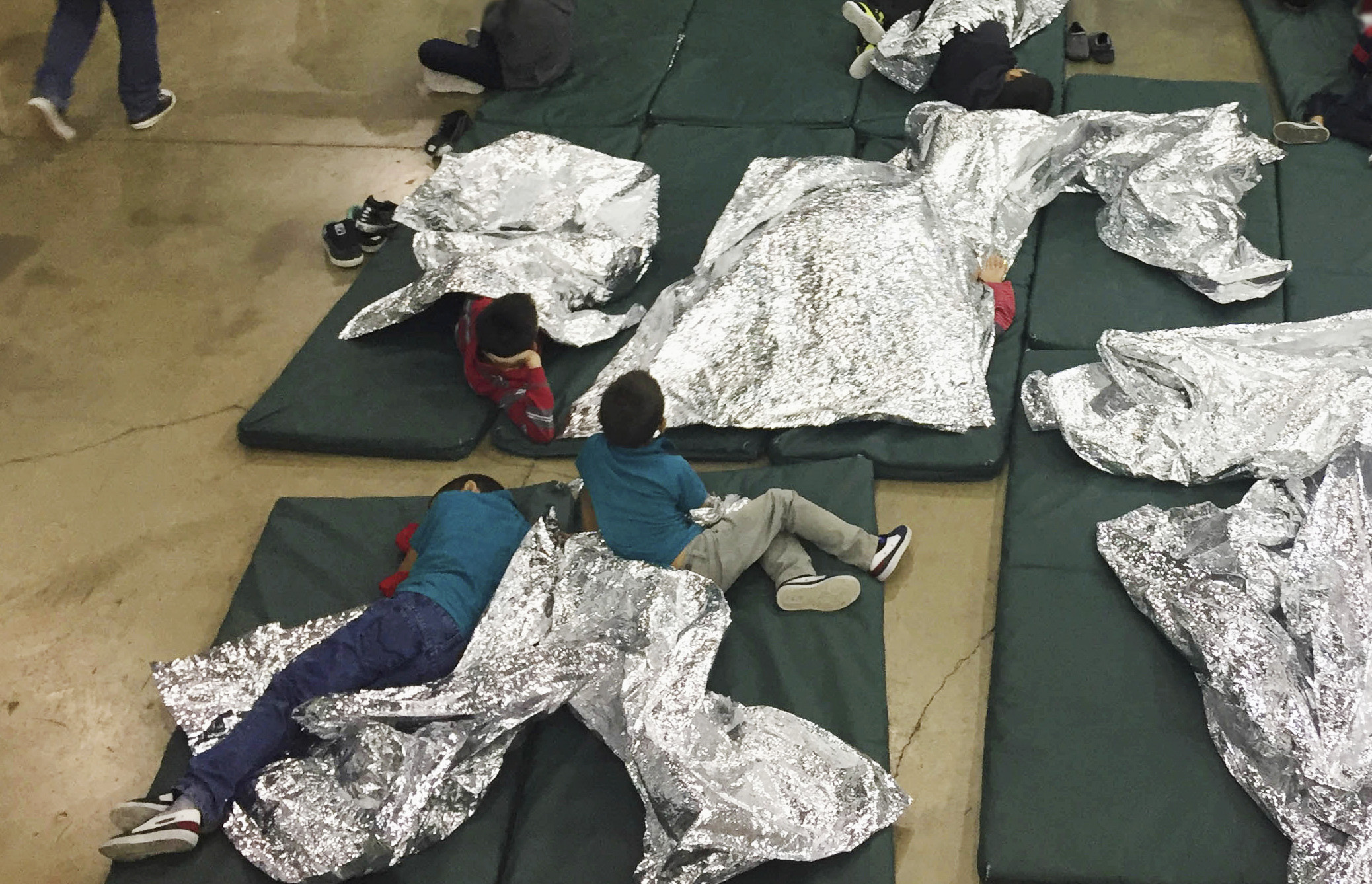 Slide 1 of 28: People who've been taken into custody related to cases of illegal entry into the United States, rest in one of the cages at a facility in McAllen, Texas, Sunday, June 17.