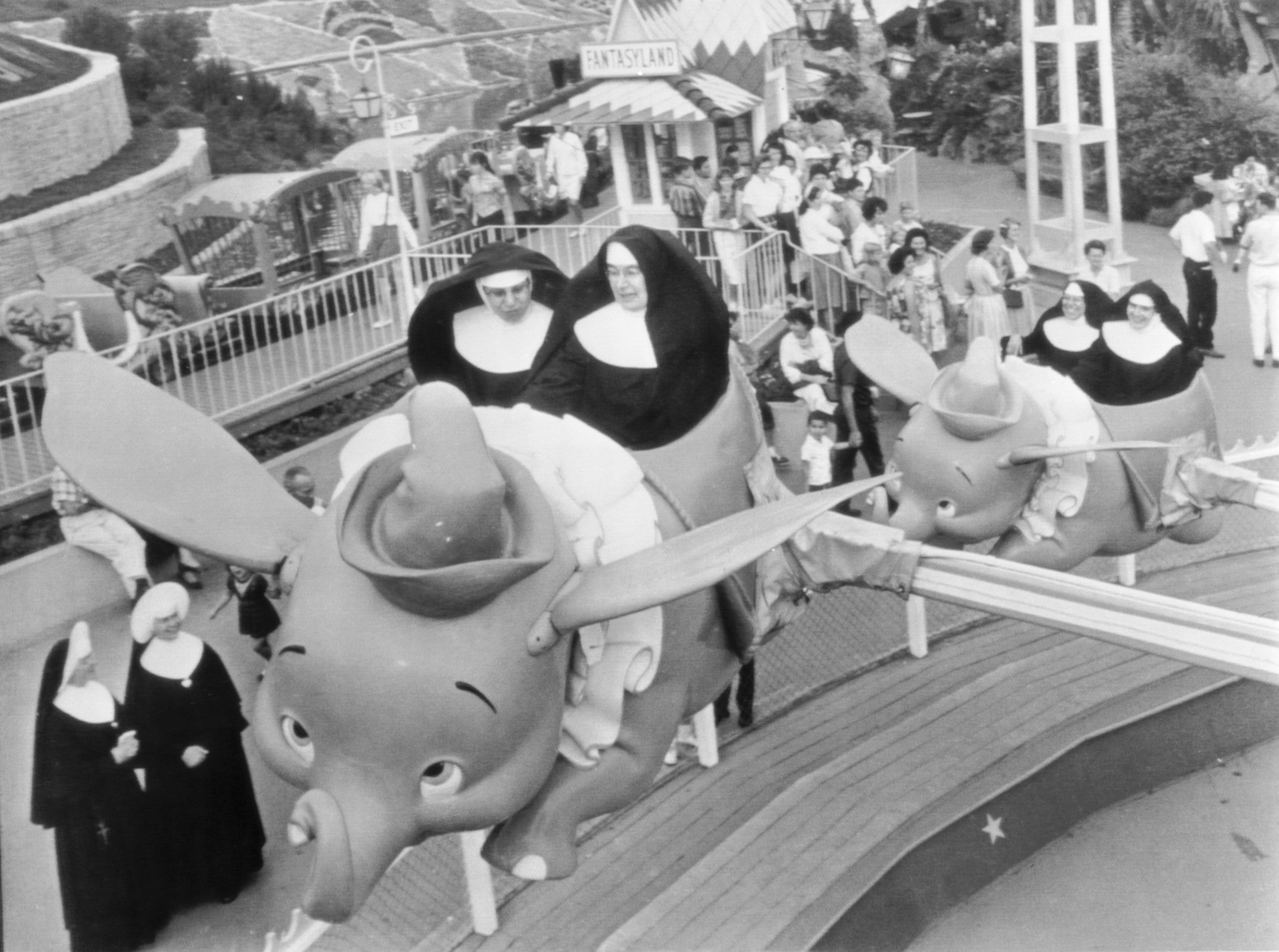 Slide 17 of 33: Catholic School Day at Disneyland and Sisters Mary William and Mary Alfred take the first elephant as Sisters Mary Yvonne and Mary Joachin follow close behind as they join the children in a ride on "Dumbo" the flying elephant at Disneyland.