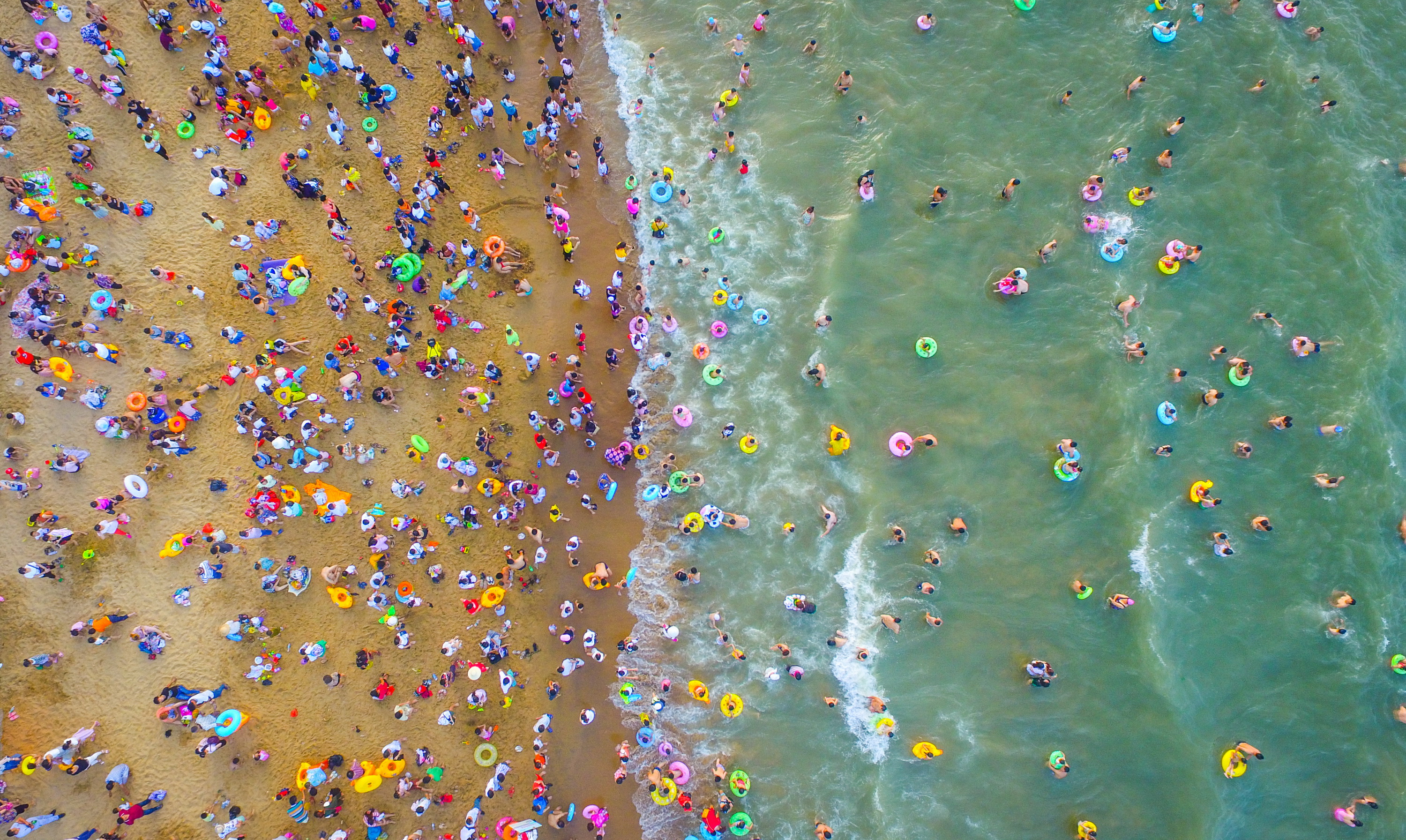 Slide 9 of 39: HAIKOU, CHINA - MAY 30:  Aerial view of crowd at beach on May 30, 2017 in Haikou, Hainan Province of China. Thousands of people came to the beach in Haikou on the Dragon Boat Festival (aka Duanwu Festival).  (Photo by VCG/VCG via Getty Images)