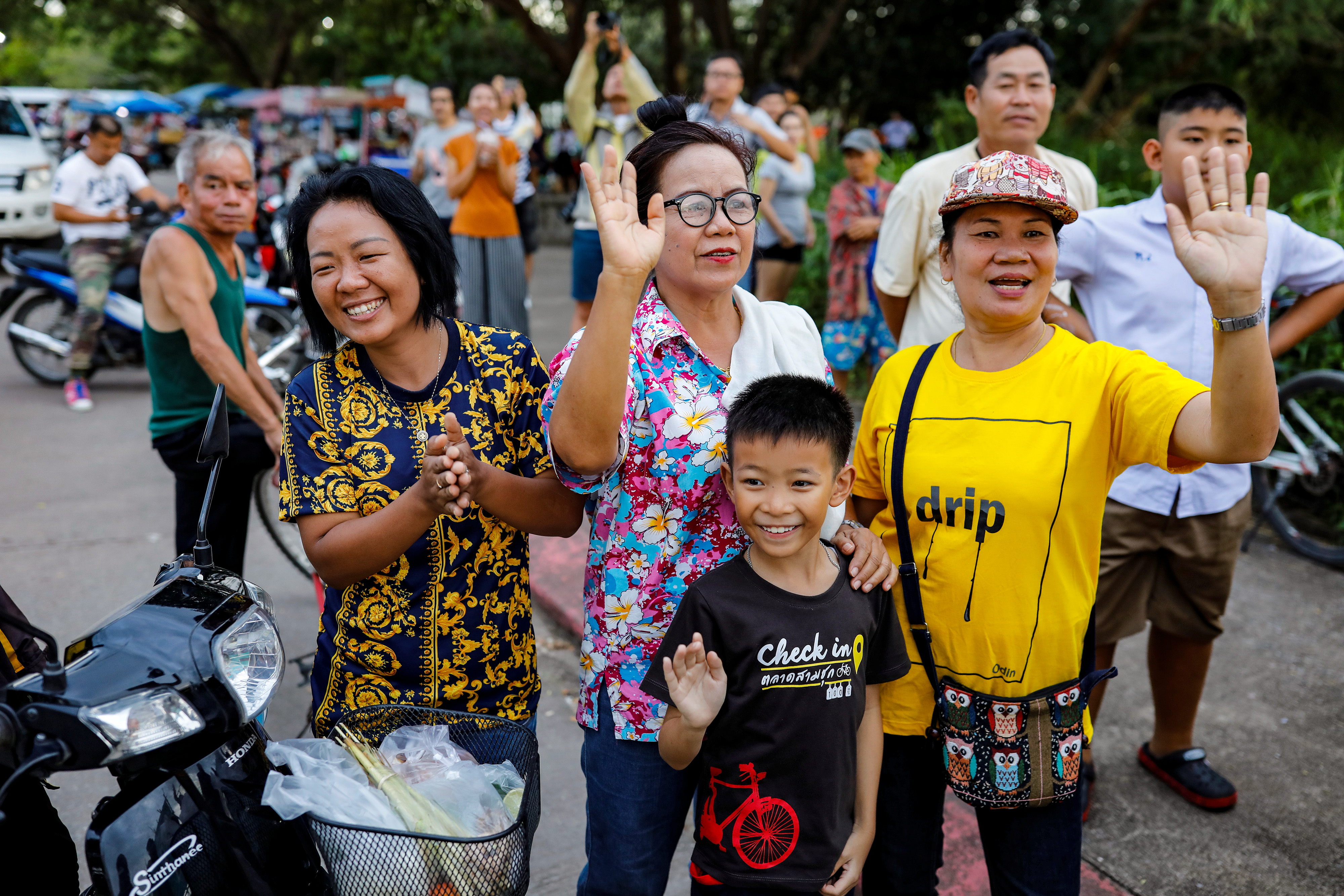 Slide 3 of 84: Onlookers wave as an ambulance carrying rescued schoolboys leaves a military airport in Chiang Rai, Thailand, July 10, 2018.