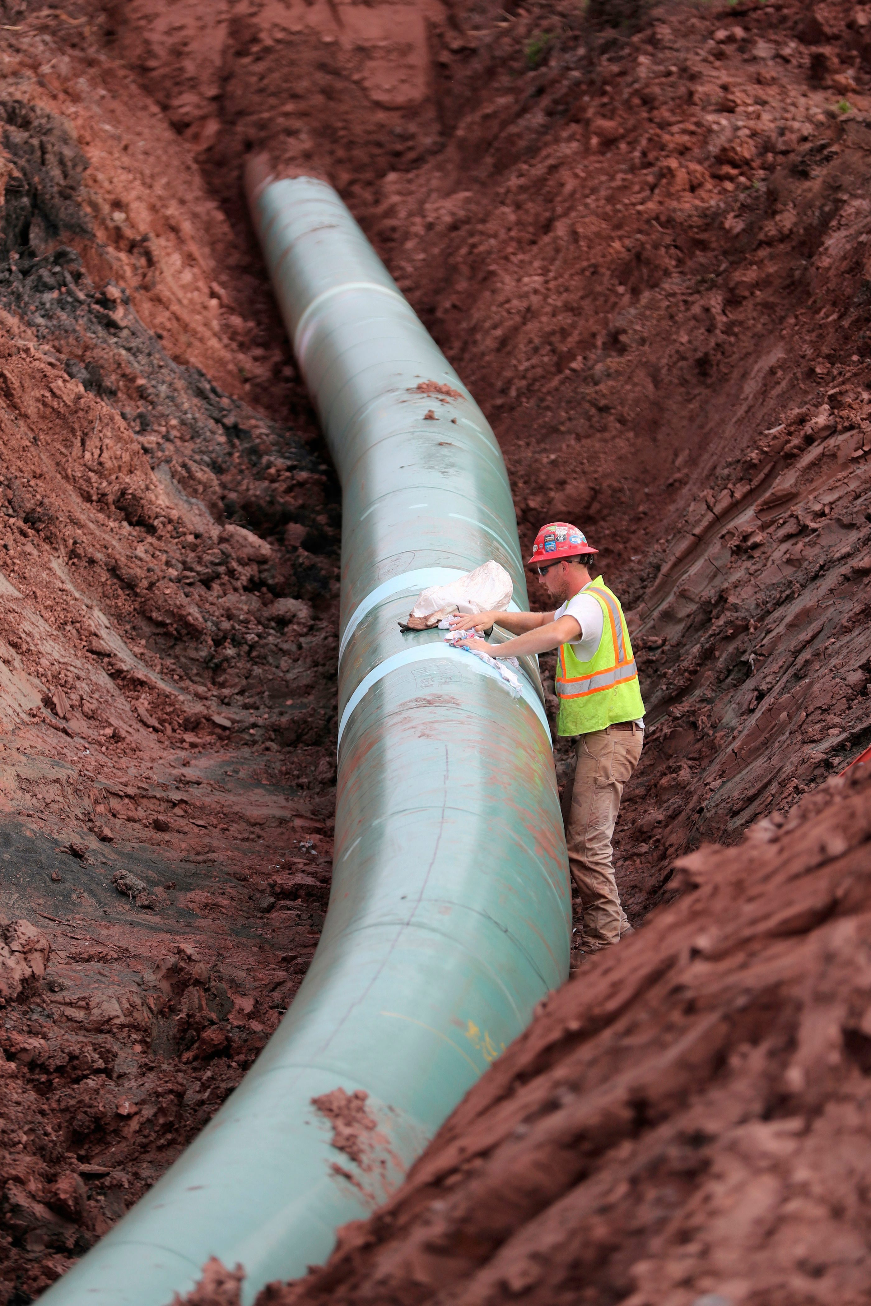 In this Aug. 21, 2017, file photo, a pipe fitter lays the finishing touches to the replacement of Enbridge Energy's Line 3 crude oil pipeline stretch in Superior, Minn.