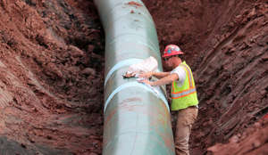 In this Aug. 21, 2017, file photo, a pipe fitter lays the finishing touches to the replacement of Enbridge Energy's Line 3 crude oil pipeline stretch in Superior, Minn.
