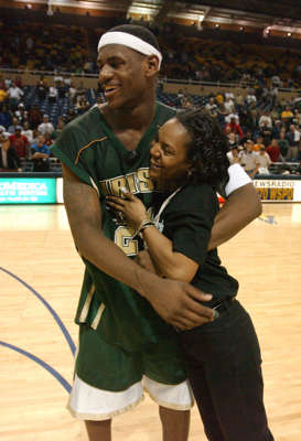 a man standing in front of a crowd: LeBron James celebrates with his mother, Gloria James, Saturday, March 15, 2003, after a win against Ottwa-Glandorf during the Ohio High School Athletic Association Boys' basketball Regional Tournament in Toledo, Ohio.