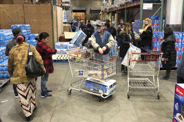Slide 2 of 95: Shoppers wait their turns to pick up toilet paper that had just arrived at a Costco store, Saturday, March 7, 2020, in Tacoma, Wash. Within minutes, several pallets of toilet paper and paper towels were sold out as people continue to stock up on necessities due to fear of the COVID-19 coronavirus. (AP Photo/Ted S. Warren)