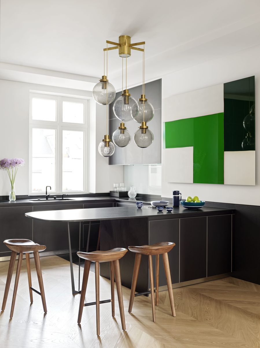 <p>After revising the layout of this modern kitchen and moving it to the heart of the <a href="https://www.veranda.com/home-decorators/a30145144/le-berre-vevaud-paris-apartment/">19th-century Paris loft</a>, design duo <a href="https://leberrevevaud.com/">Le Berre Vevaud</a> selected eye-catching artwork by <a href="https://www.tomhendo.com/">Tom Henderson</a> and blown-glass Lustre globes to act as the room's main focal points. The stools from <a href="https://bassamfellows.com/">Bassam Fellows</a> surround the Zimbabwe granite counters.</p>