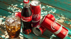 a bottle of beer on a table: coca-cola bottles and cans. coke is a blue-chip stocks