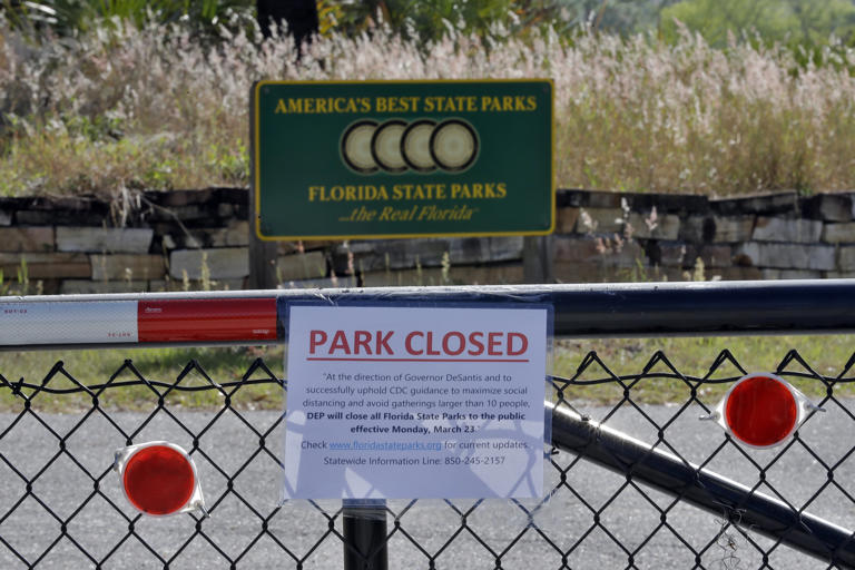 A closed sign, attached on the outside fence at the Alafia River State Park, is shown Monday, March 23, 2020, in Lithia, Fla. Florida Gov. Ron DeSantis has issued an order closing all of Florida's 175 state parks, trails and historic sites to help stop the spread of the coronavirus. (AP Photo/Chris O'Meara)