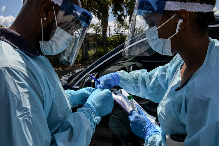 Medical personnels take medical samples at a "drive-thru" coronavirus testing lab set up by local community centre in West Palm Beach 75 miles north of Miami, on March 16, 2020.