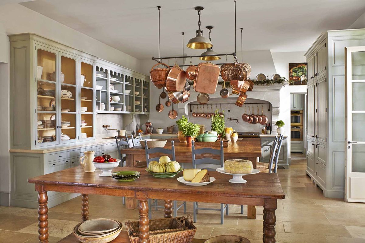 <p>In this <a href="https://www.veranda.com/decorating-ideas/a26976859/provence-farmhouse-transforms-beautiful-gardens/">Provence farmhouse</a> kitchen, designer <a href="https://www.sblonginteriors.com/">Susan Bednar Long</a> warmed up the white walls, painted Wimborne White by <a href="https://www.farrow-ball.com/en-us">Farrow & Ball</a>, with a wooden island and farm table, limestone flooring, and a large collection of copper pots. The cabinets are painted Light Blue by <a href="https://www.farrow-ball.com/en-us">Farrow & Ball</a>. The pendant lights are from <a href="https://urbanelectric.com/">The Urban Electric Co.</a></p>