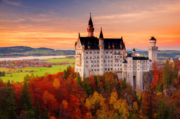 Slide 12 de 65: Scenic sunset view on Neuschwanstein Castle with colorful sky and autumn trees. Bavaria, Germany.