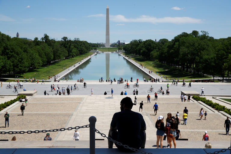 A man sits on the top step of the Lincoln Memorial as people gather by the Lincoln Memorial Reflecting Pool in Washington, Saturday, May 2, 2020. The District of Columbia is under a stay-home order for all residents in an effort to slow the spread of the new coronavirus.