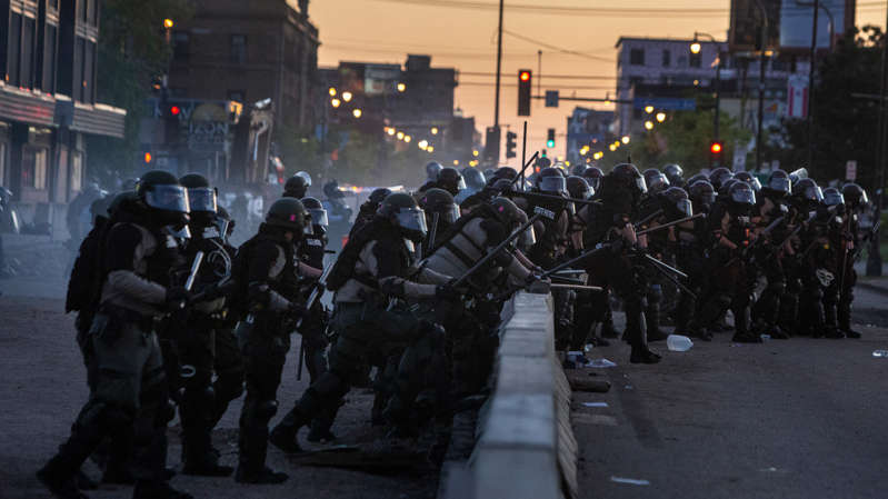 a group of people walking down the street: Police officers in riot gear at a protest in Minneapolis on Saturday.