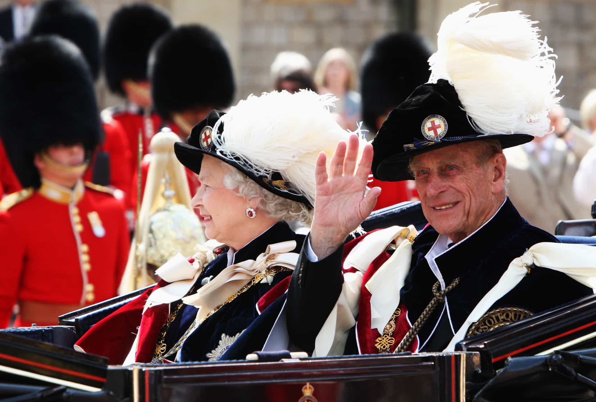 La reina y el príncipe vestidos con trajes de terciopelo, insignias y sombreros con plumas dejando la capilla de St. George en el Garter Day, en el 660.º aniversario de la orden, el 16 de junio de 2008.