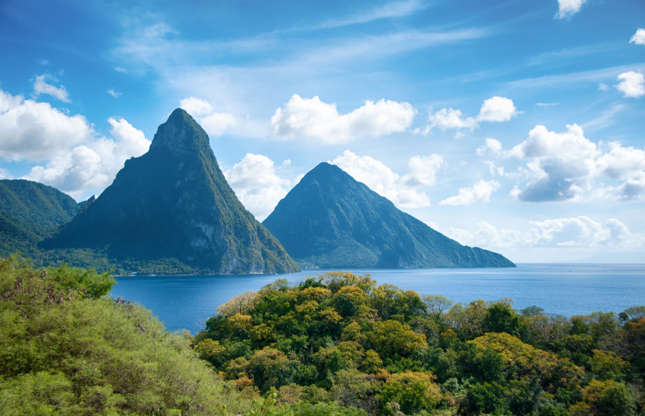 Slide 3 of 31: An unmistakable sight in St Lucia, The Pitons are one of the island's best-known views. The two volcanic plugs are now covered in a dense green jungle and the Pitons – Gros Piton and Petit Piton – are home to no less than 245 different plant species, including eight rare tree species, and 27 bird species, five of them endemic.