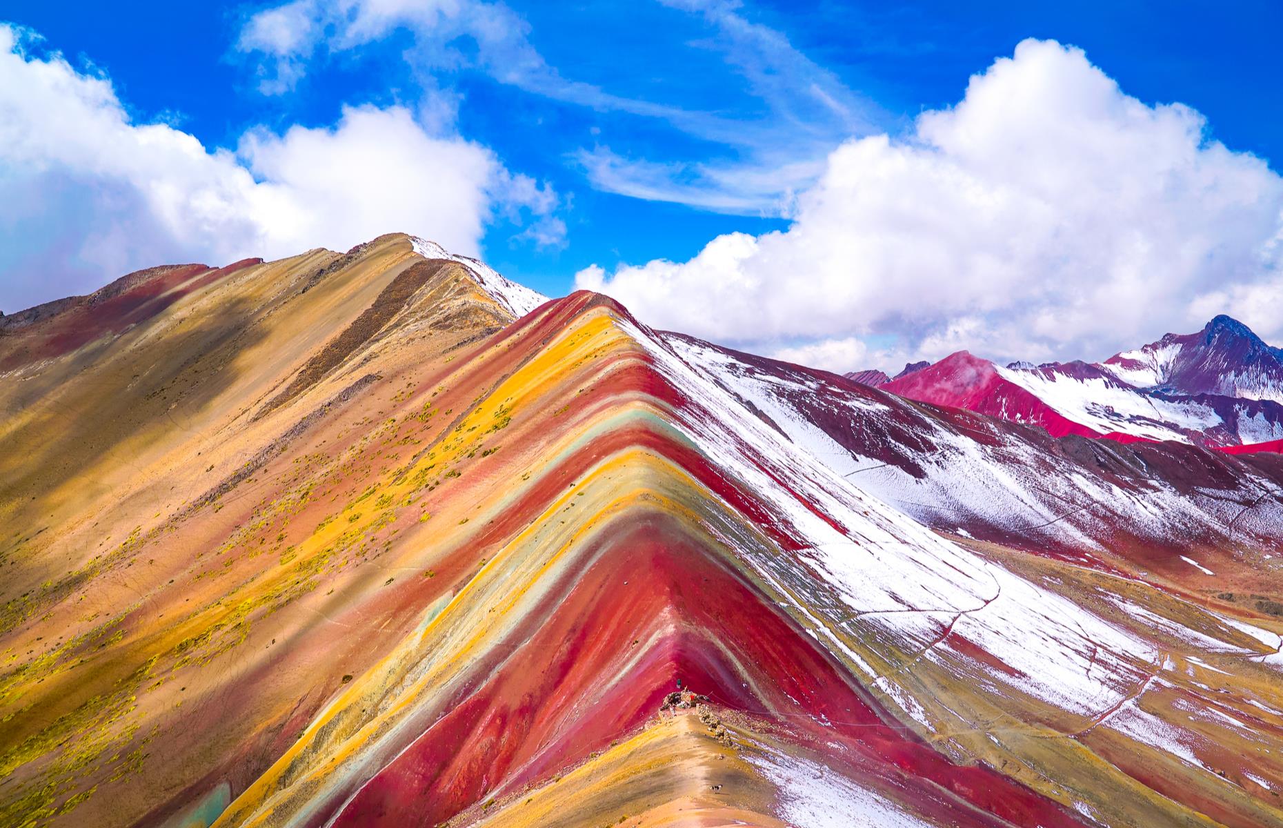 Slide 26 of 31: This multicolored mountain in the Peruvian Andes is not man-made despite what its perfectly symmetrical layers might make you think. The colorful bands, ranging from pink and red to yellow and green, are the result of sedimentary layers forming from mineral deposits over the years. Interestingly, the colorful bands haven't always been visible. Rapid ice melt revealed the unique colors of the mountains only in the 2010s. Discover more amazing images of the world's most colorful natural wonders.
