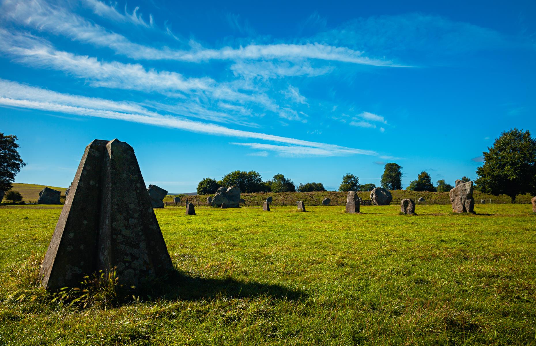 Slide 3 of 31: The vast and rich henge monument of Avebury – a complex of Neolithic and Bronze Age ceremonial sites – contains three stone circles, one of which is the largest in all of Europe. Its main outer megalithic circle measures more than 1,000 feet (300m) across and originally consisted of around 100 standing stones. It encloses two smaller circles. The southern circle focused on a central point, the great Obelisk, which was removed in the 18th century. It would have been the largest stone in the circle at 21 foot (6.4m) high.