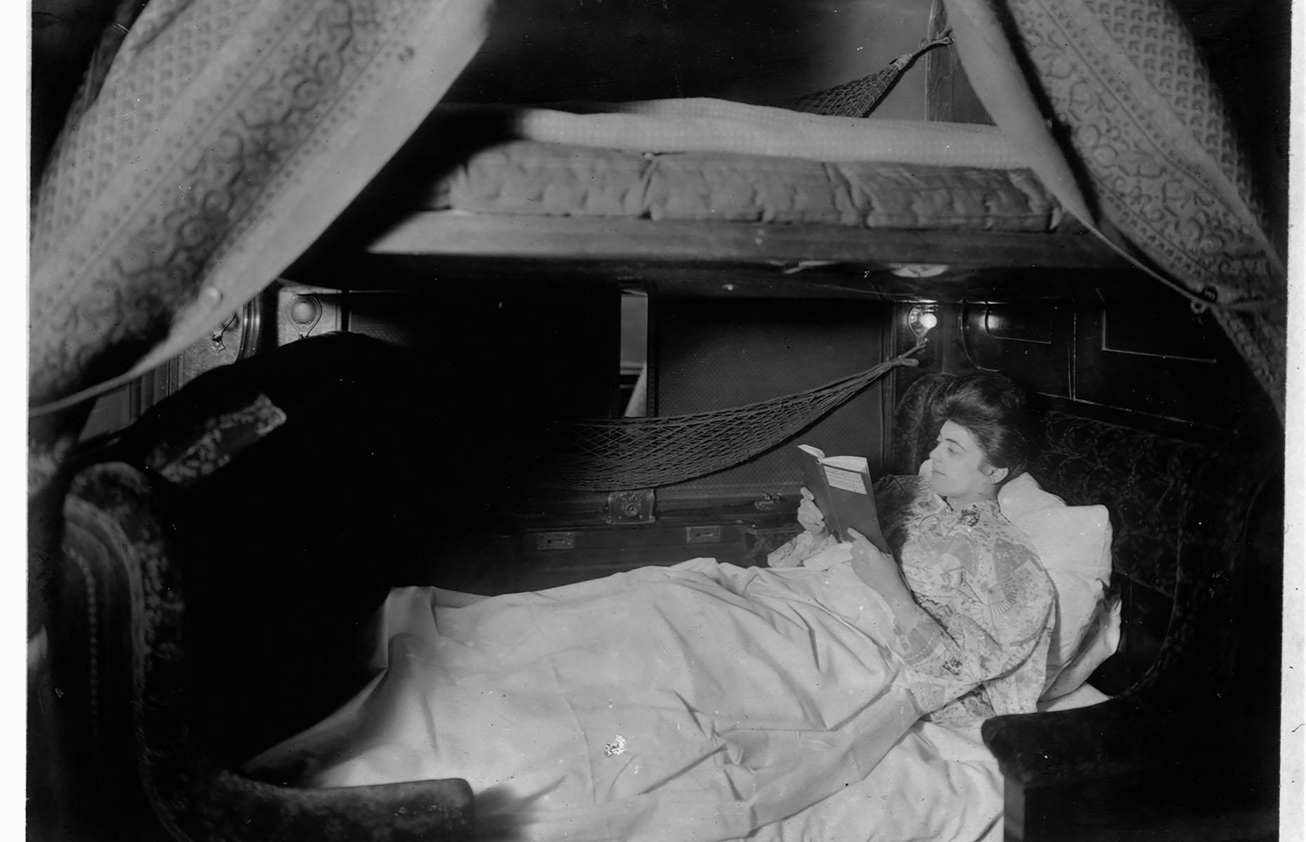 While train travel was still considered a luxury, especially for the wealthier passengers, rather than just a mode of transport, comfort was a priority. Photographed in 1905, this woman is enjoying reading a book before bed in her spacious bunk on a sleeping car.