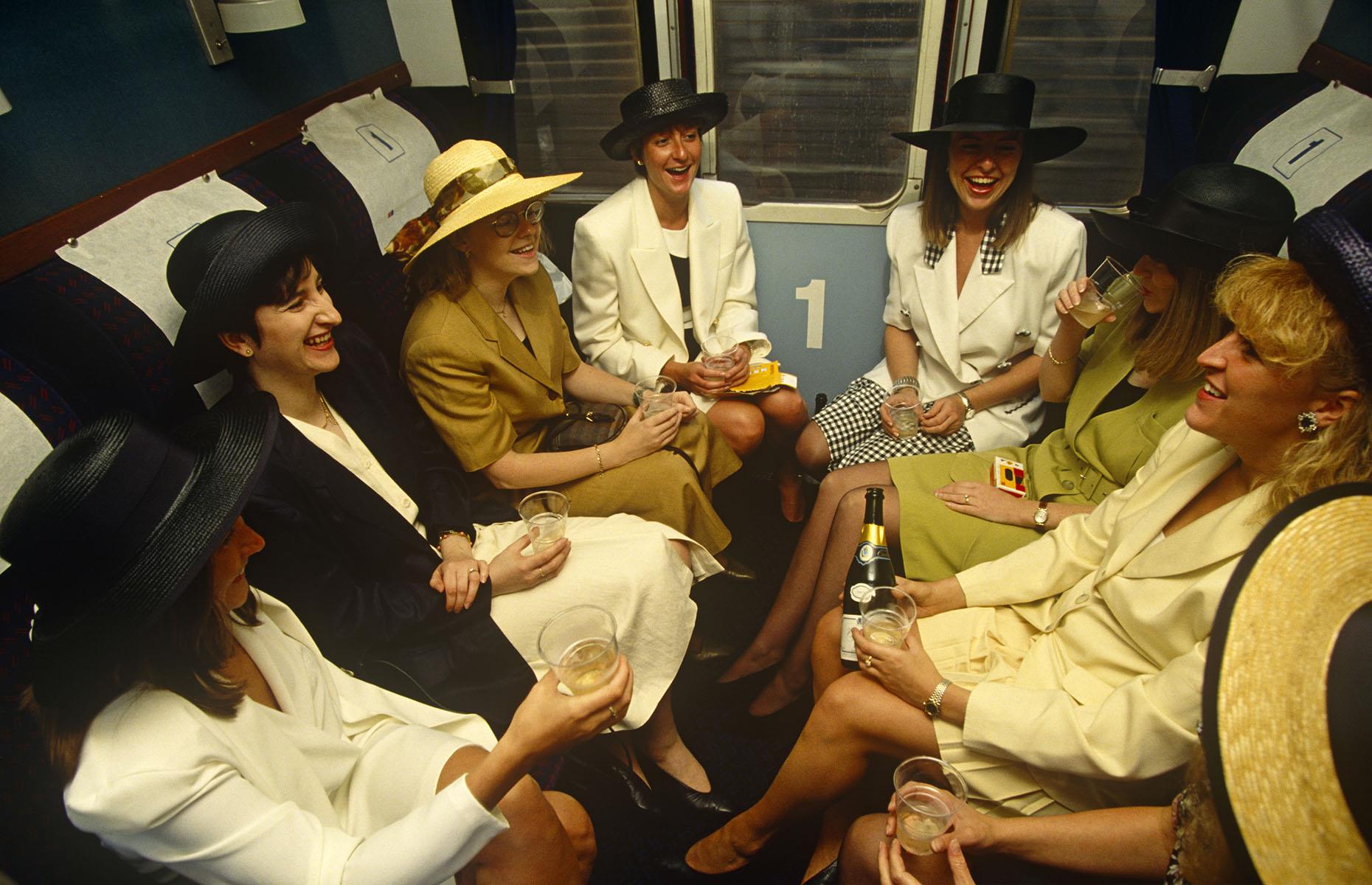 Throughout the ages trains have played a significant part in people's lives. While private car ownership has steadily risen since the 1980s, trains are still often a significant part of special occasions like this one. Here, captured in 1993, a group of women are traveling from London Waterloo to Royal Ascot in Berkshire for Ladies Day during the Royal Ascot racing week.